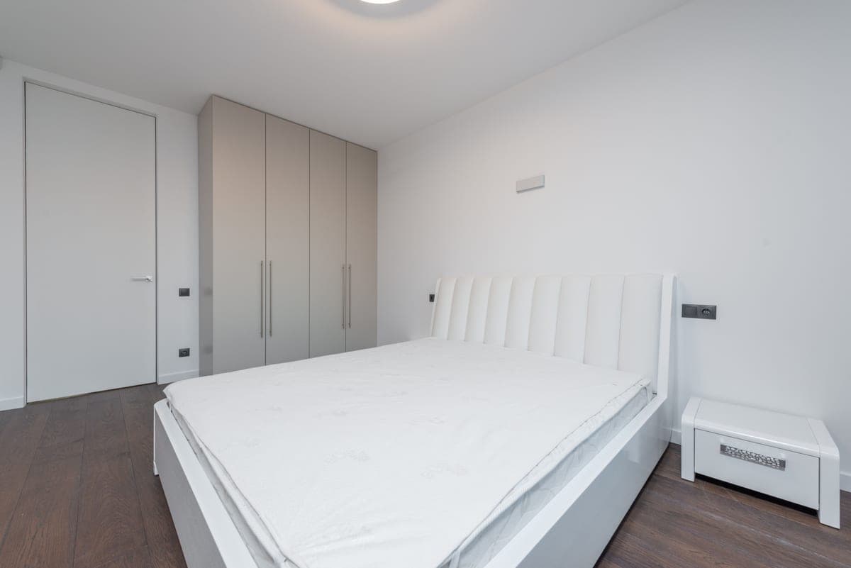 A bare mattress on a bed frame in a minimal room
