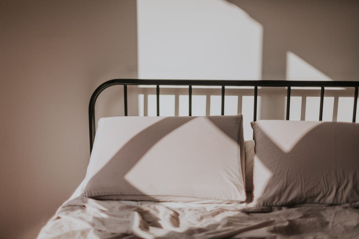 A white pillow on a bed in morning light