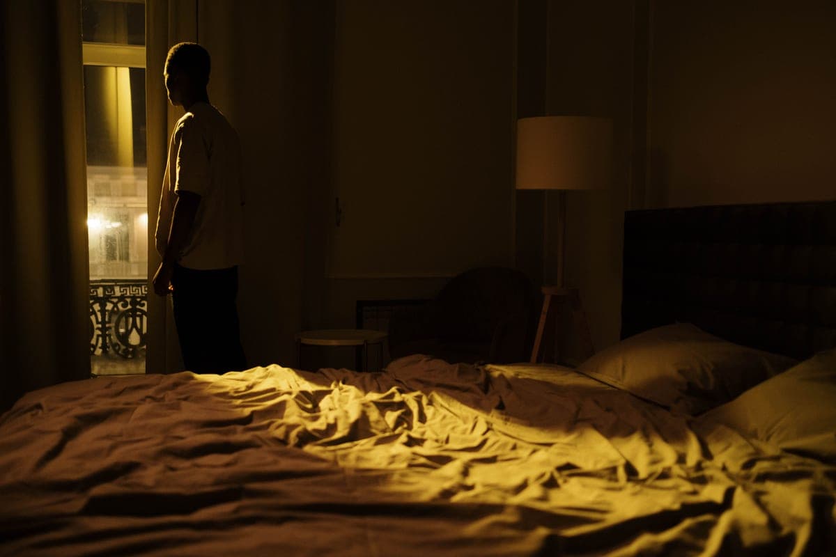 A dark bedroom at night with light through the window