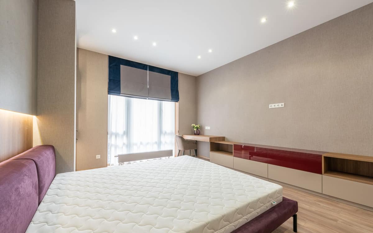 A bare mattress resting on its bed base in a bedroom