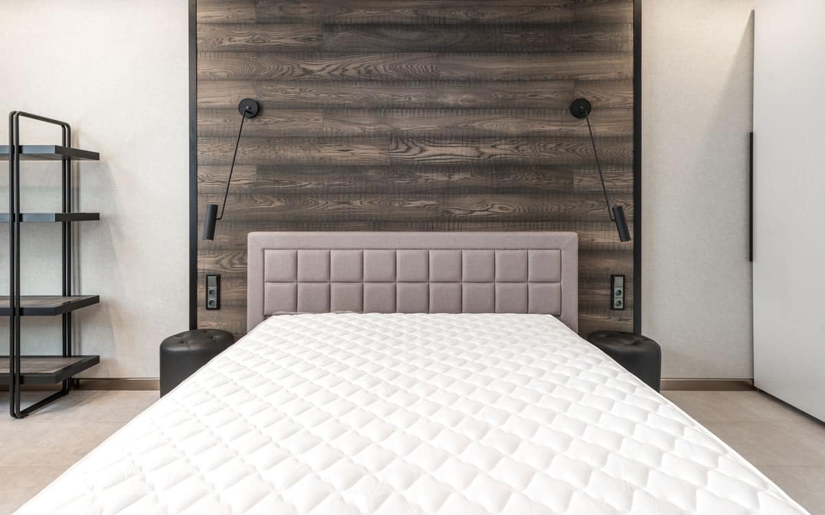 A bare quilted mattress top on a bed, before the sheets go on