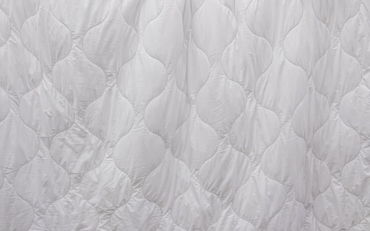A close-up of white quilted mattress-pad fabric