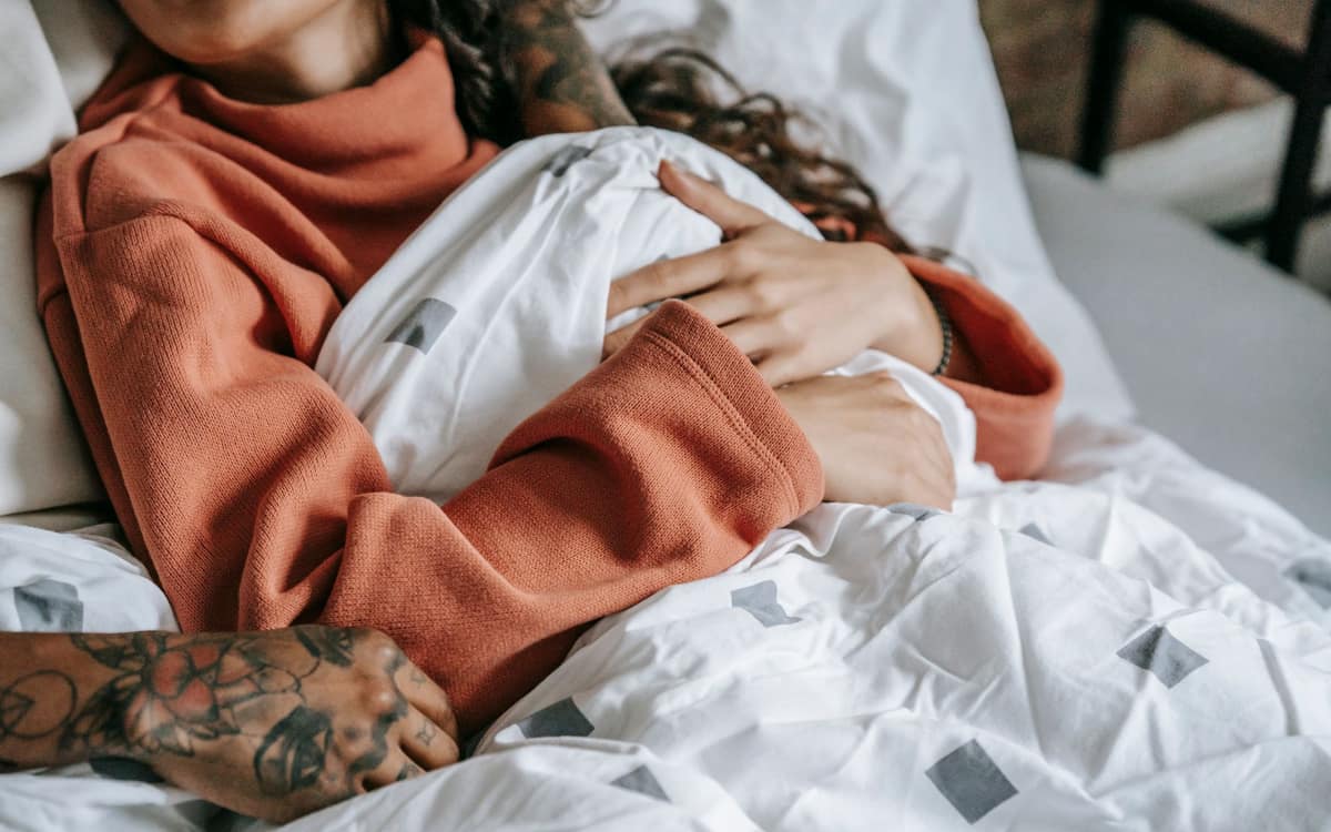 A sleeper bundled in a sweater under a duvet