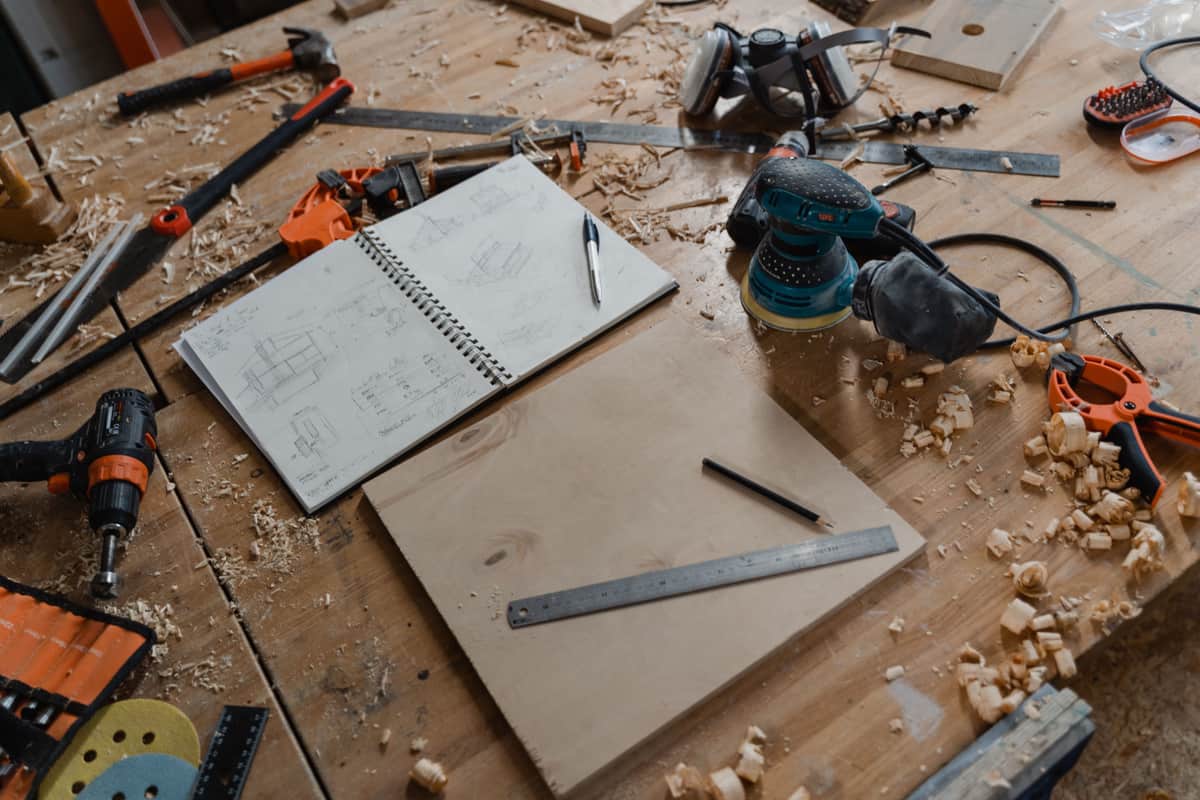 A workbench with tools, a notebook and measuring equipment