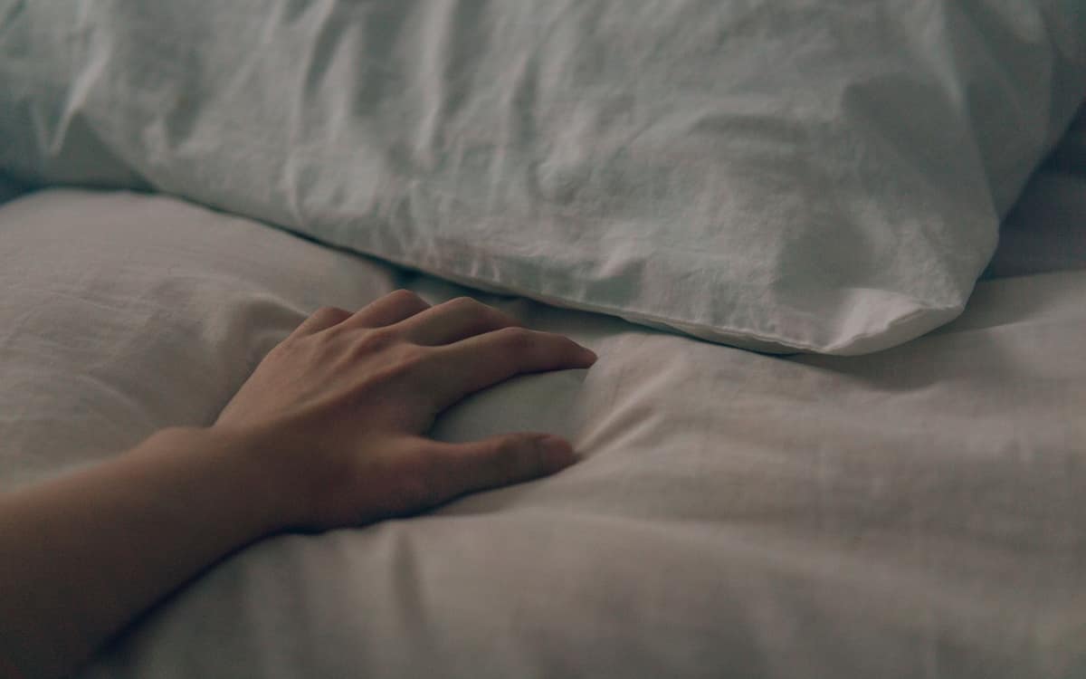 A hand resting on a cool white pillow