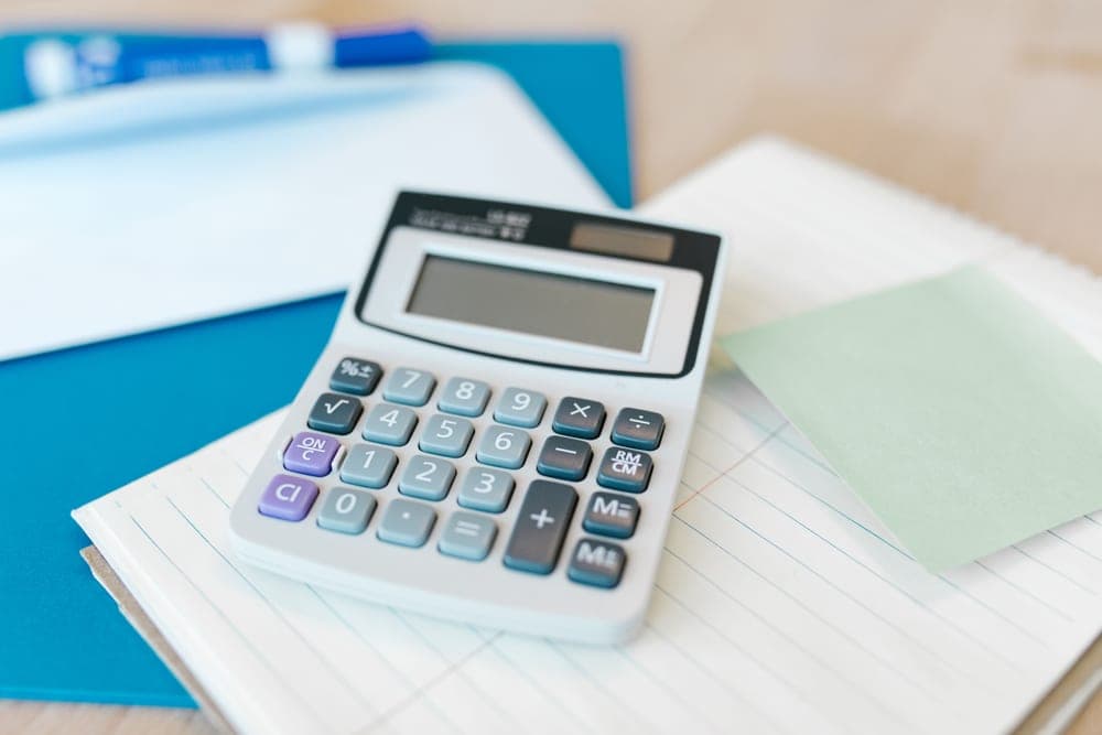 A calculator and notepad on a desk