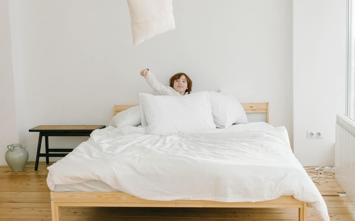 A single supportive pillow on a made bed in morning light