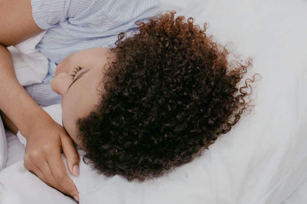 A person sleeping on their side in bed