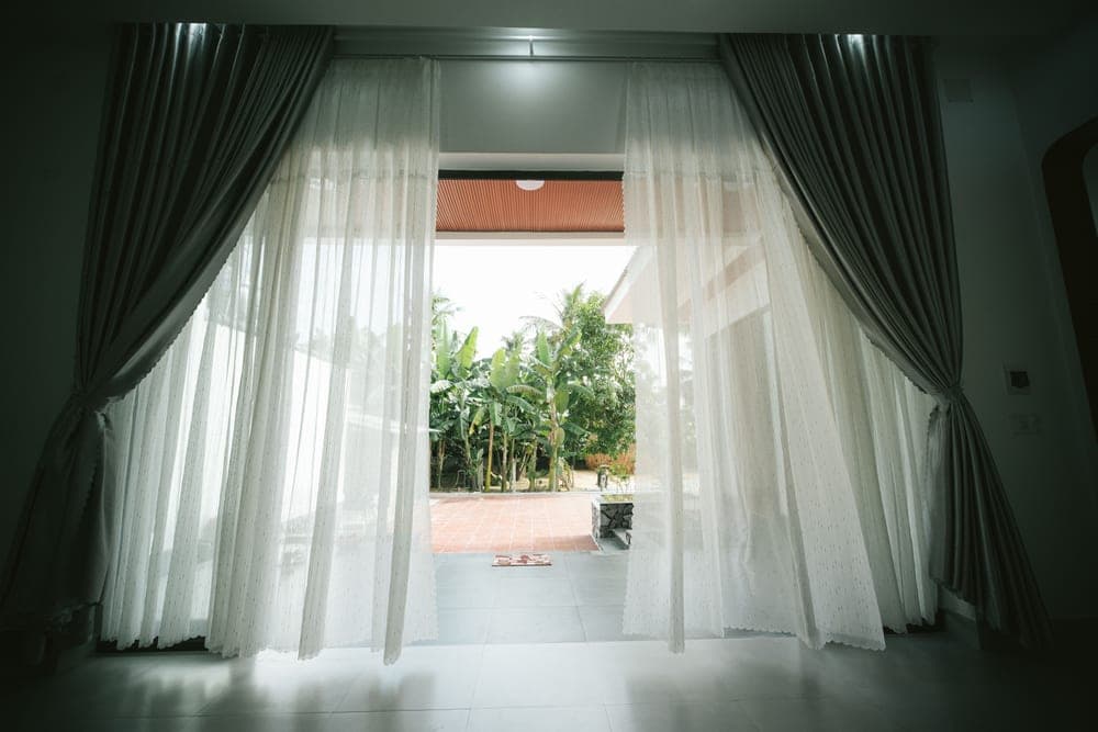 An open window with a curtain moving in the breeze