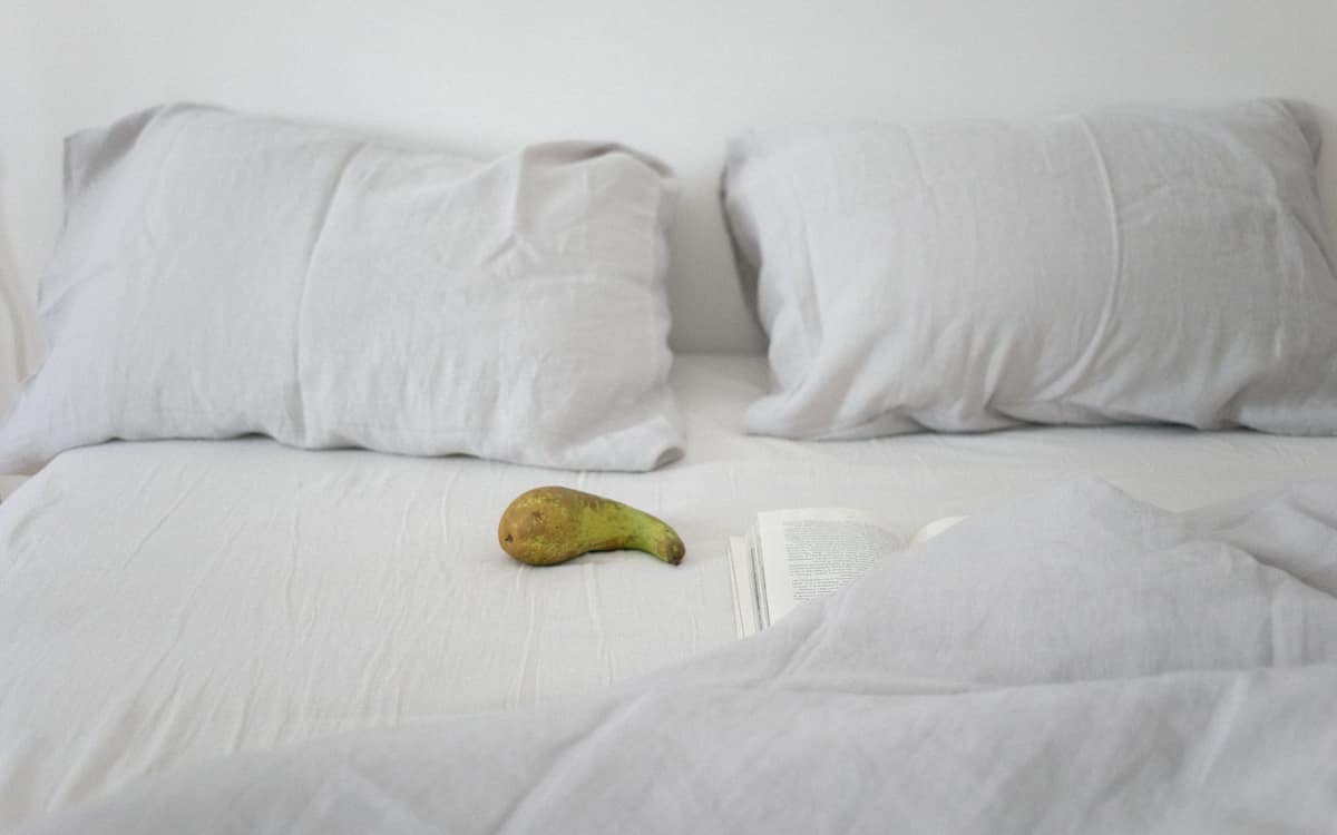 A flat sheet folded back over the duvet on a made bed