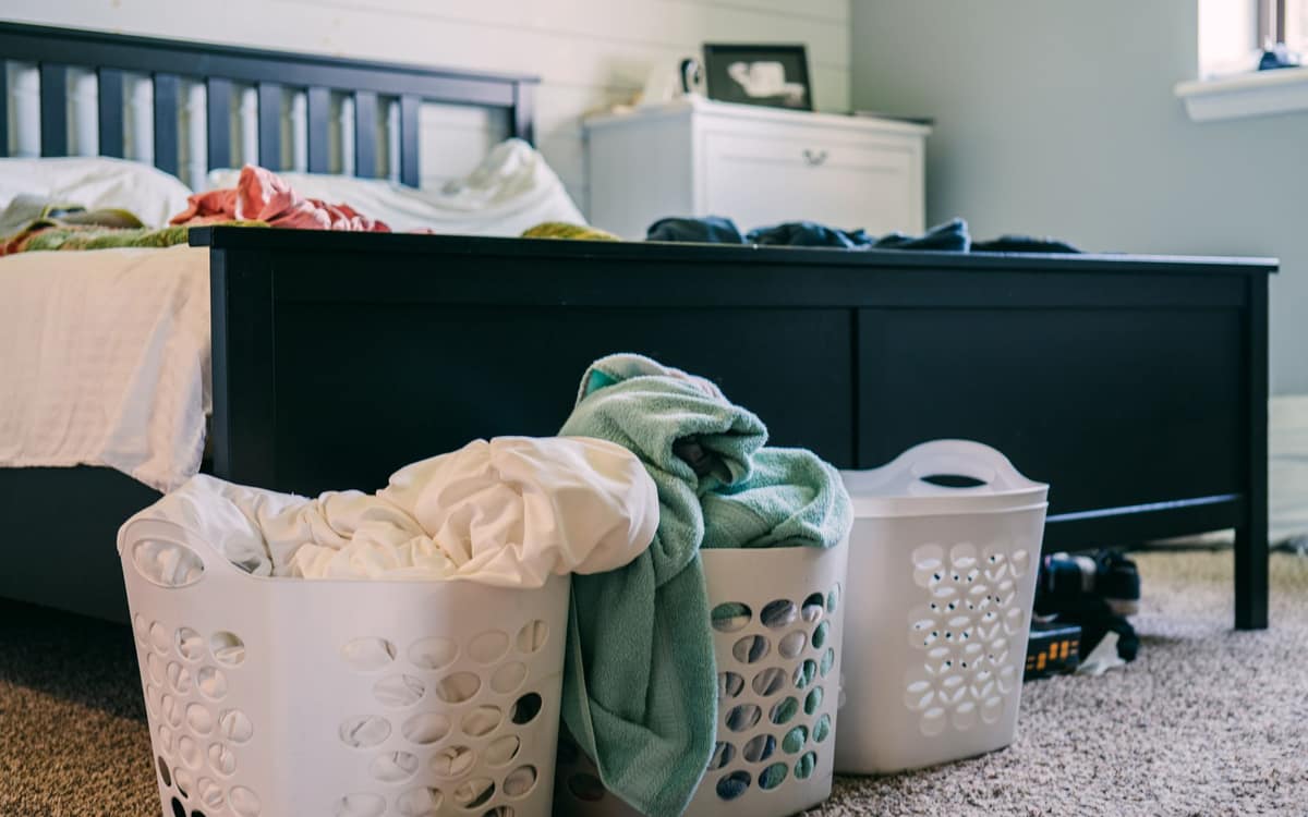 Laundry baskets of stripped bedding at the foot of a bed